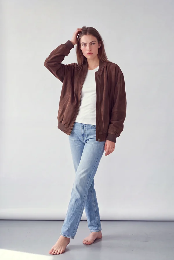 Stüdyoda kahverengi süet bomber ve kot pantolon giyen model